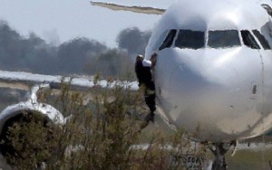 Un miembro de la tripulación abandona el avión saltando desde la ventanilla de la cabina.